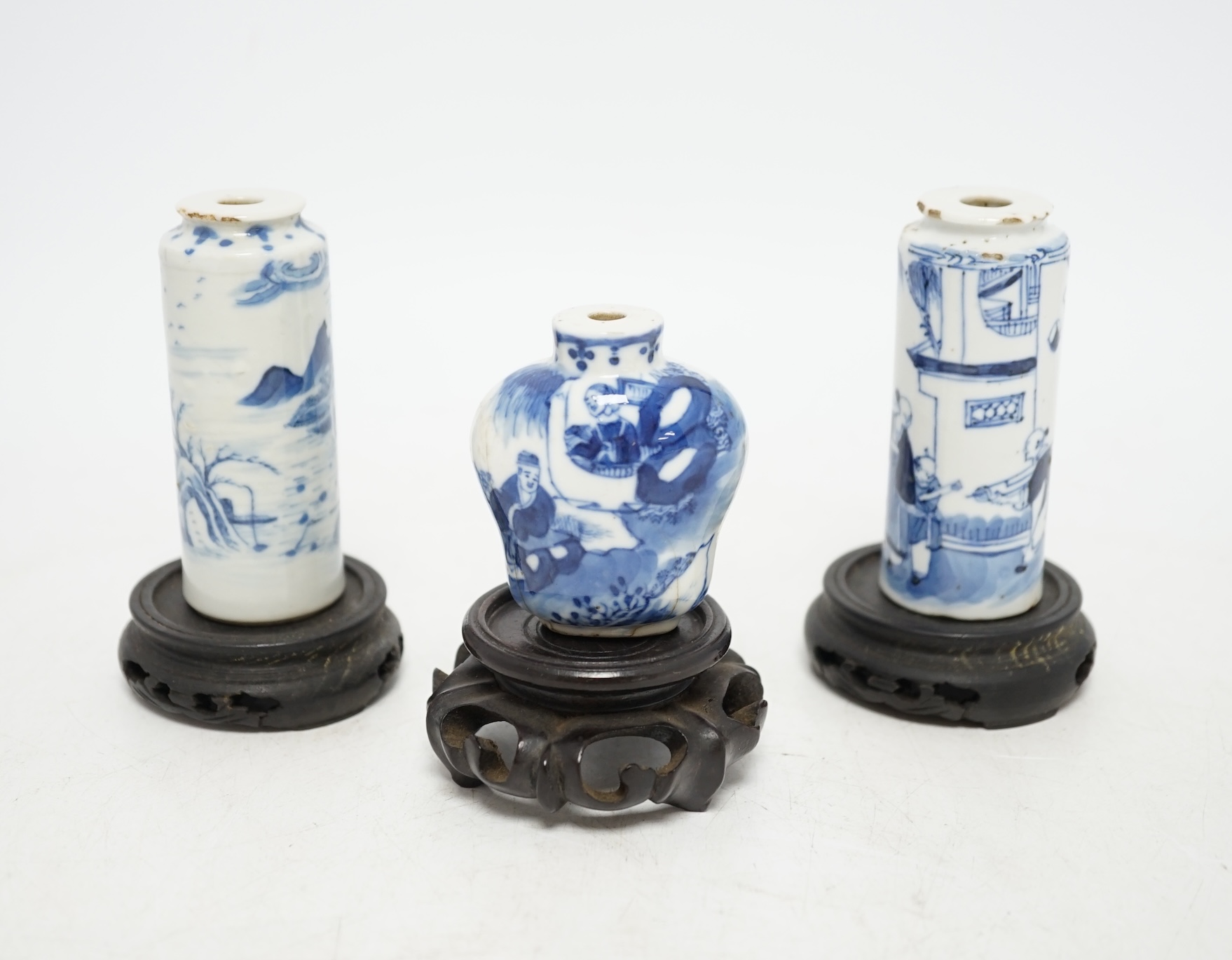 Three Chinese blue and white snuff bottles and three hardwood stands, largest 8cm high. Condition - poor to fair